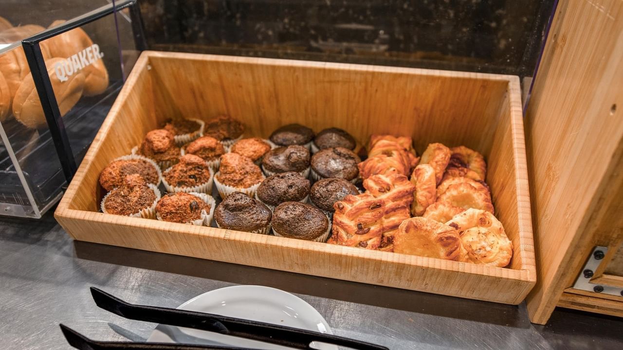 Wooden tray displaying assorted donuts and pastries at Coast Calgary University Area Hotel by APA