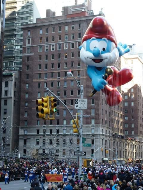 large Papa Smurf balloon floating above a crowded city street during a festive parade near Warwick New York 