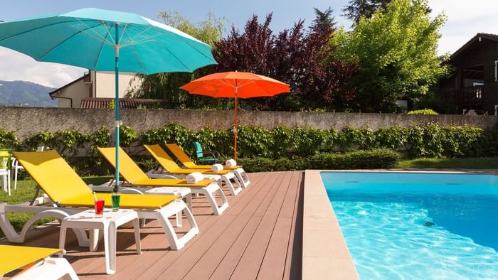 Outdoor pool loungers on a sunny day at The Originals Hotels