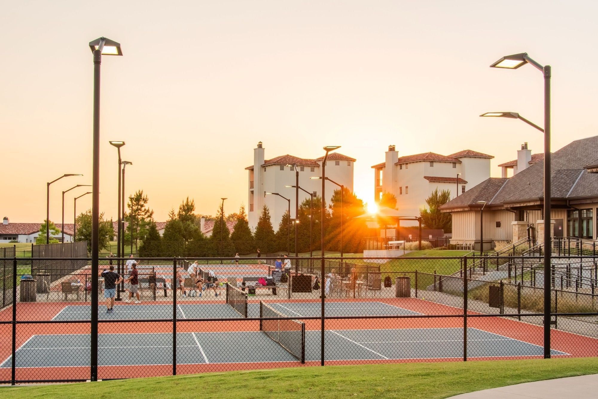 Outdoor pickleball courts at sunset with players, tall light poles, and a clubhouse at Shangri-La Resort and Golf Club