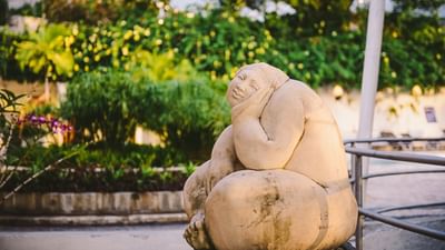Stone Buddha statue seated in a garden with lush tropical foliage and purple flowers at Hotel Montana Haiti