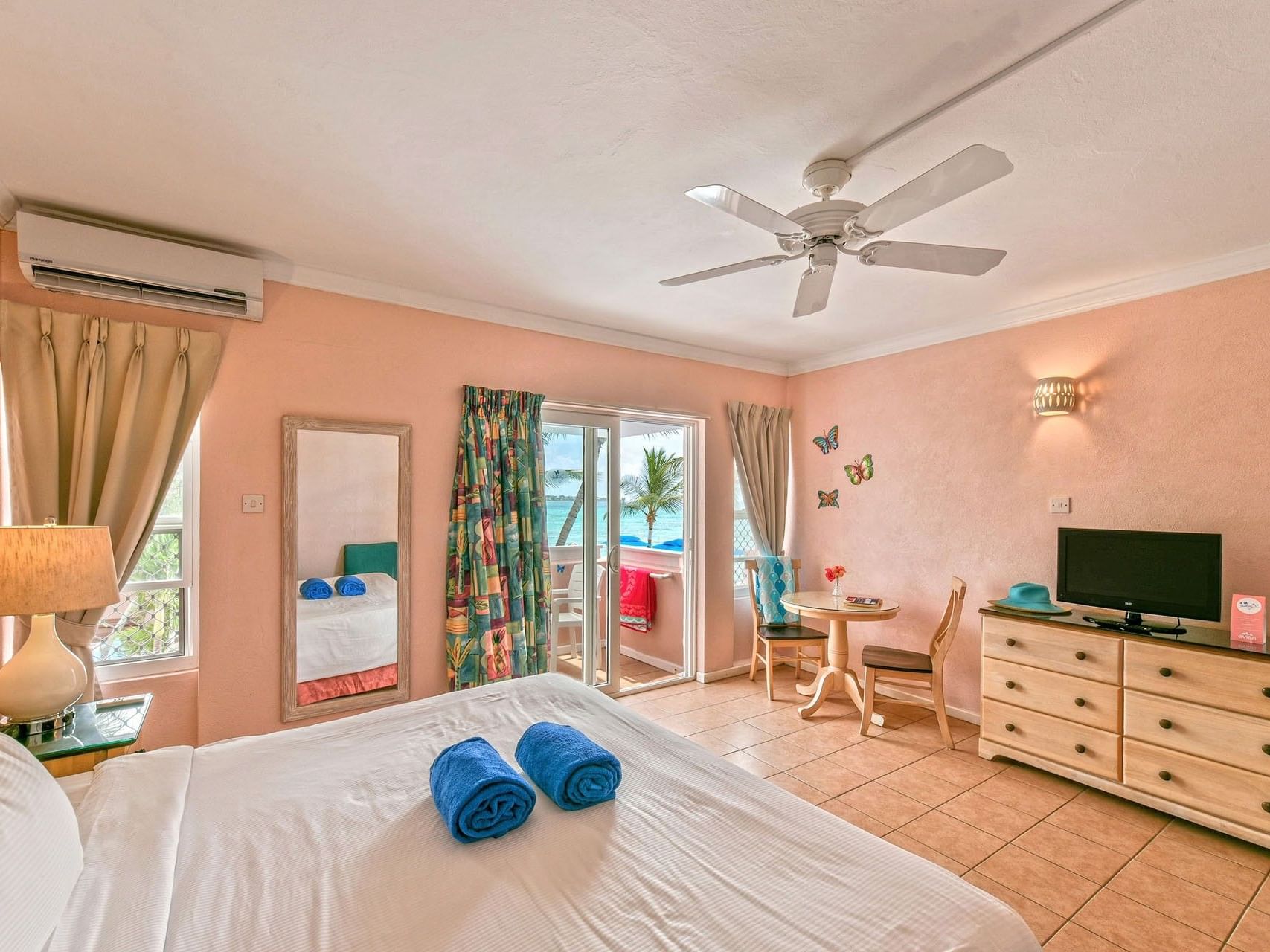 Superior Room – Mixed View featuring pink walls, TV, and blue towels on the bed at Butterfly Beach Hotel
