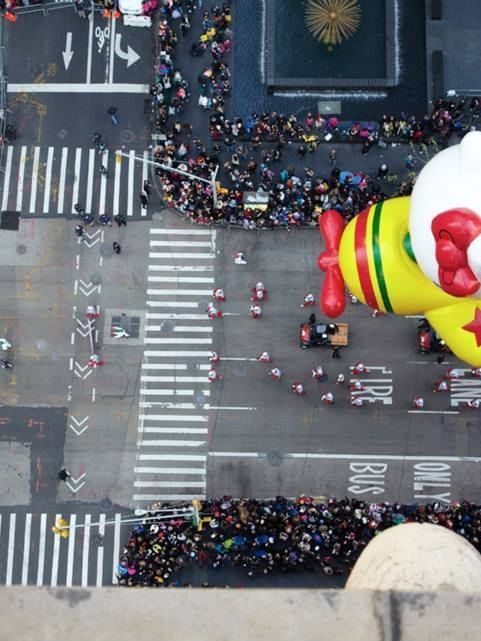 Aerial view of a giant Hello Kitty airplane balloon flying over a crowded city parade near Warwick New York
