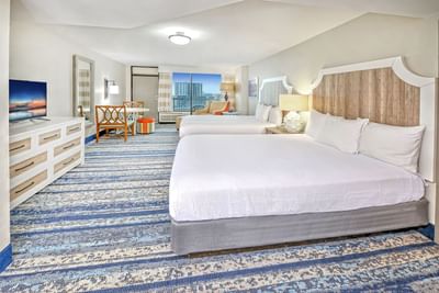 The luxurious Ocean View Room at the Daytona Bahama House Hotel with two beds, a dining area, and a balcony with city view.