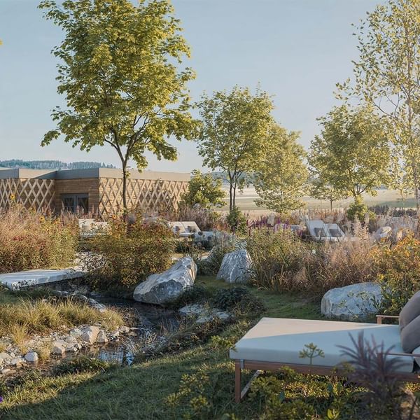 Eine luxuriöse Gartenterrasse mit Liegen, Felsen, Pflanzen und einem Haus im Hintergrund.