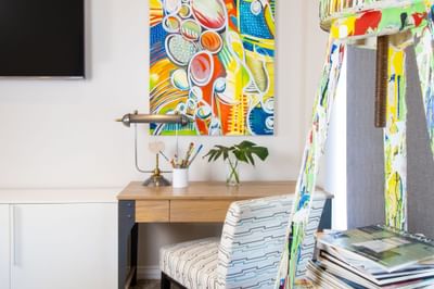 Work desk, chair, books & paintings on the wall in King Premiere Studio at Retro Suites Hotel