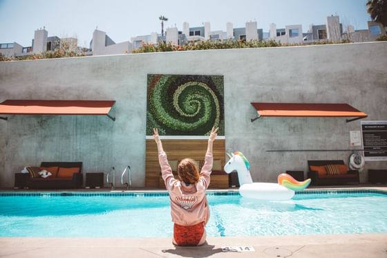 A woman enjoying time by the pool edge at Hotel Angeleno