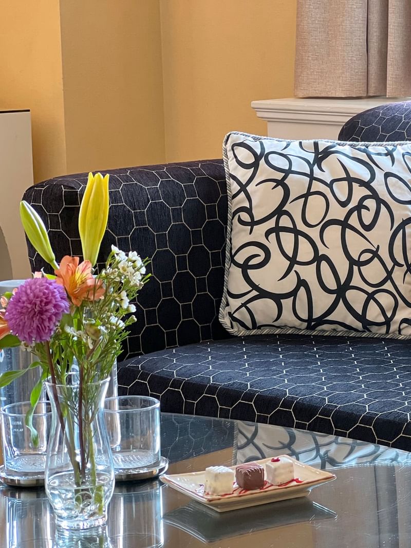 Cozy Superior Suite living area with sofa, coffee table, flowers, and window at Warwick Allerton - Chicago.