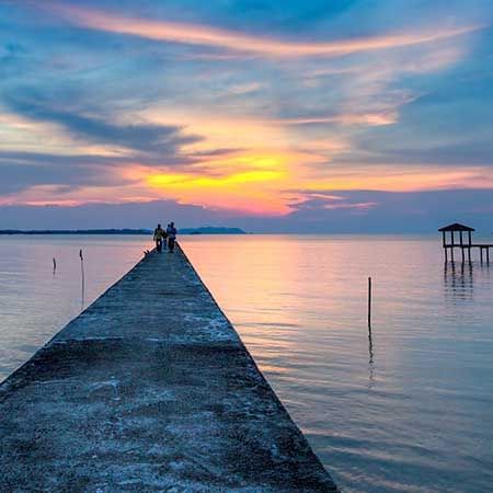 jetty with the ocean and a sunset in the background