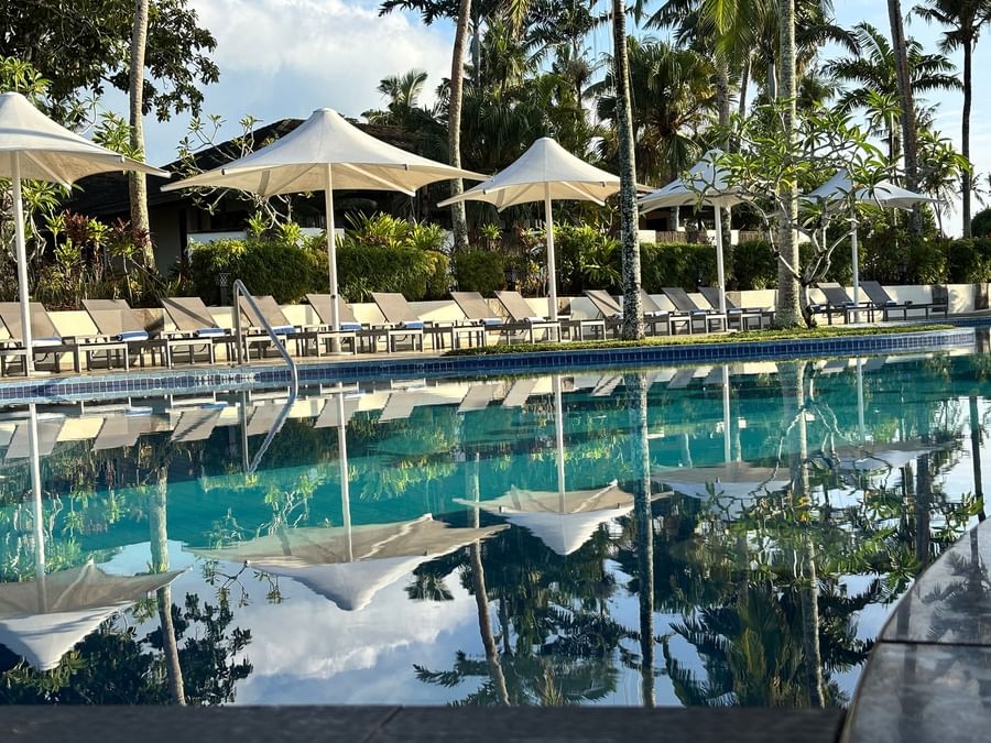 Lounge chairs under umbrellas by a serene pool at Warwick Le Lagon Vanuatu.