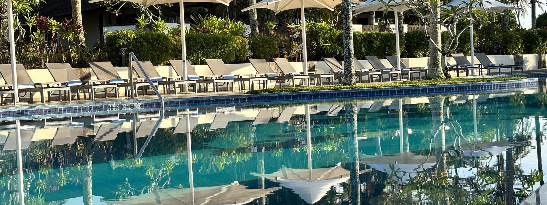 Pool and lounge chairs with umbrellas at Warwick Le Lagon - Vanuatu in Efate