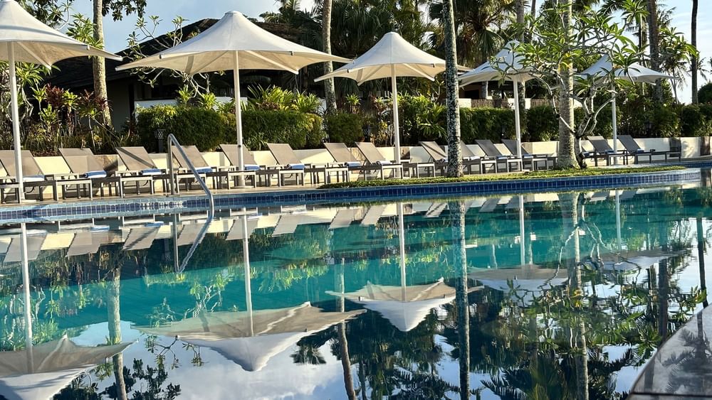 Pool and lounge chairs with umbrellas at Warwick Le Lagon - Vanuatu in Efate.