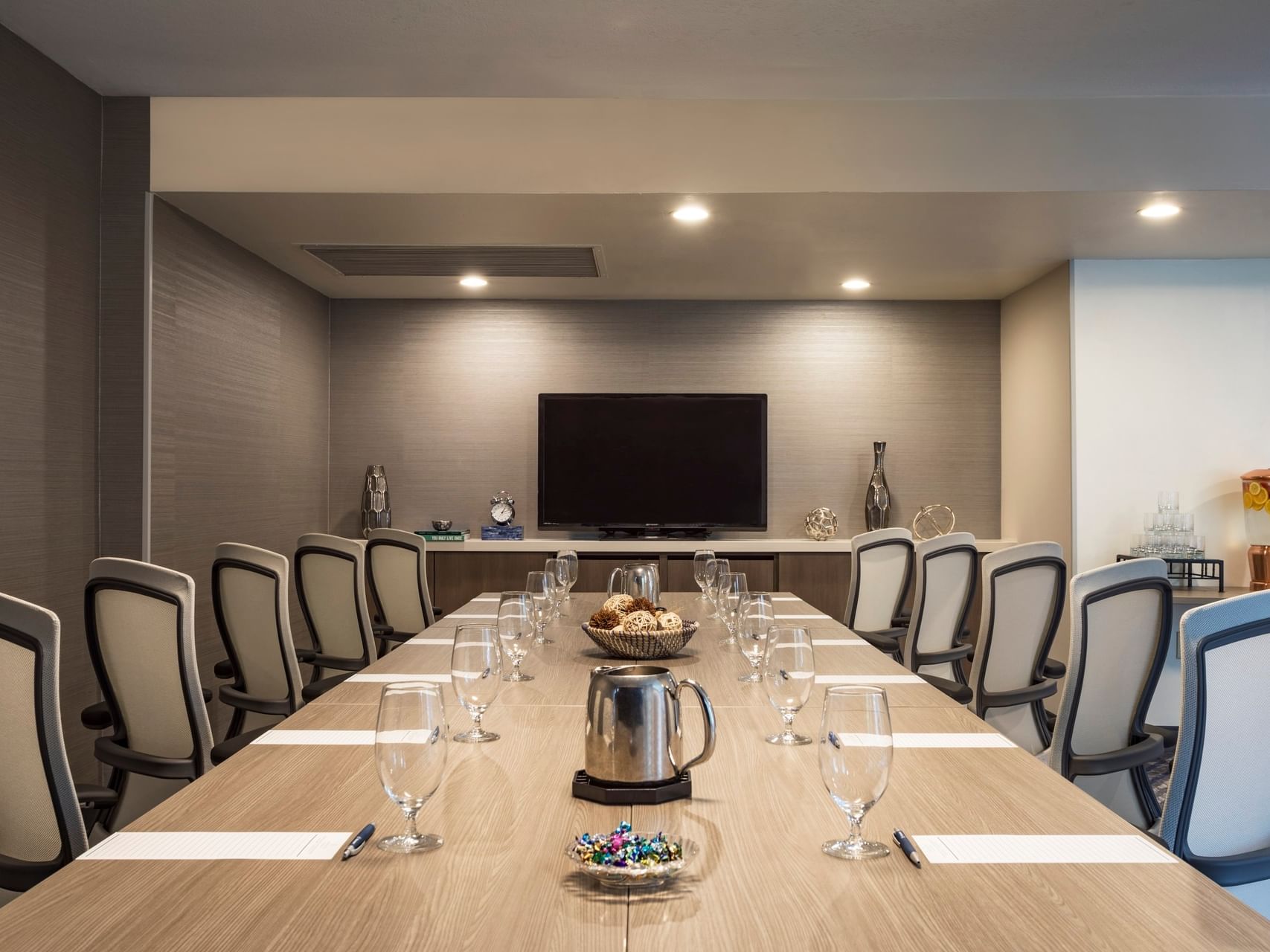 Long conference table with white executive chairs and a TV in Cape Elizabeth Room at Sable Oaks Weddings and Events
