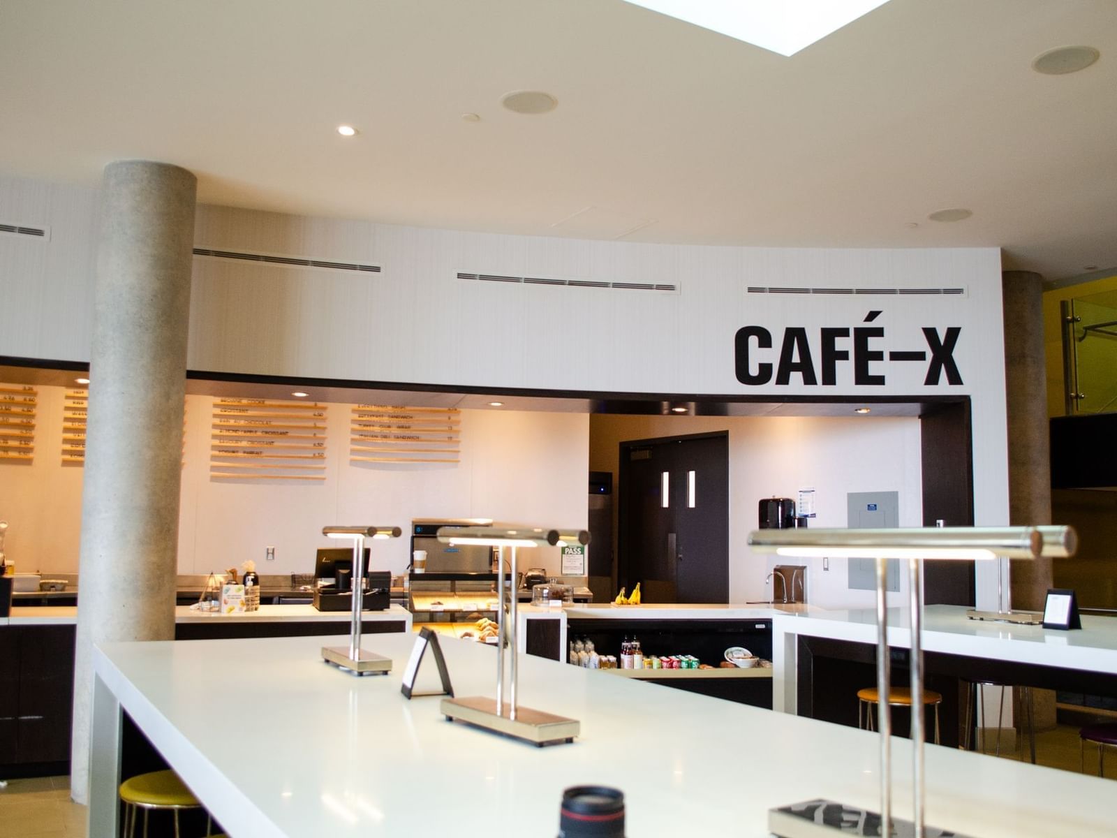 Café X interior with a counter, stools, and a sign at Hotel X, hotels in Toronto downtown