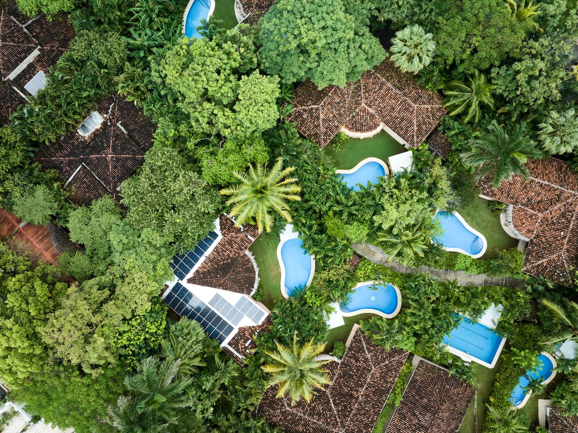 Aerial view of Cala Luna Boutique Hotel, showing tropical villas, solar panels, and sparkling turquoise pools