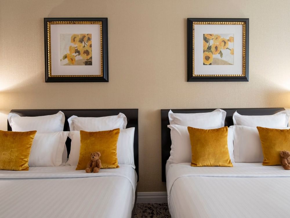 Twin beds & gold pillows by sunflower paintings in Family room with two queen beds at Warwick Paris Champs Elysées