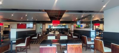 Restaurant with wooden tables, chairs, lamps & buffet area for dining in San Jose Costa Rica at D Sabana Hotel