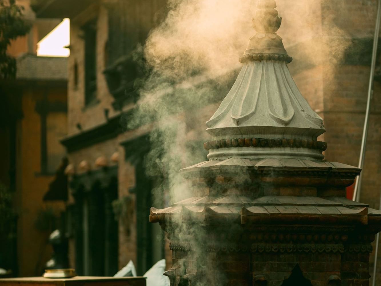 Close-up of a stone temple structure emitting wisps of smoke, featuring Nitya Puja near Dwarika's Hotel Kathmandu