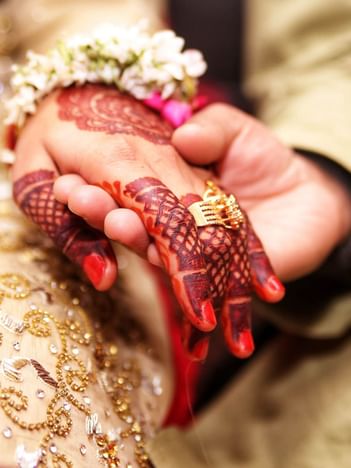 Close-up of two hands with henna, gold ring, and floral bracelet at The Saujana Hotel Kuala Lumpur