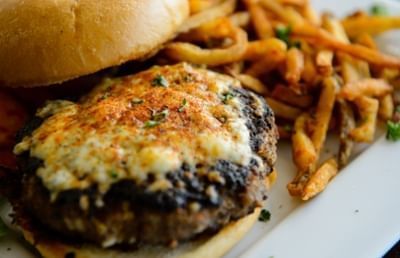 Gourmet burger patty with melted cheese served beside French fries on dish at Clemson University Conference Center & Inn