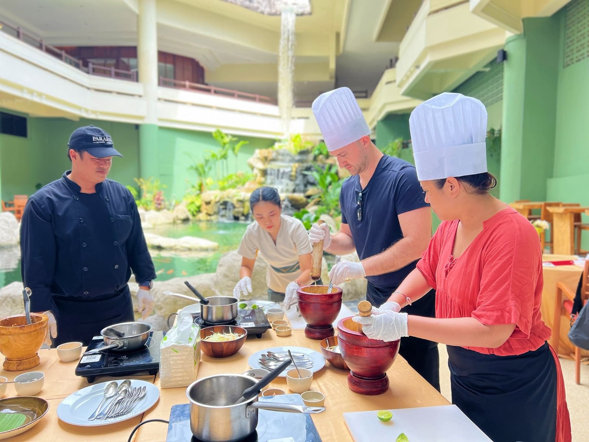 A couple is learning how to make Som Tum (Thai papaya spicy salad) in a private Thai Cooking Class at Paradox Phuket, Karon Beach