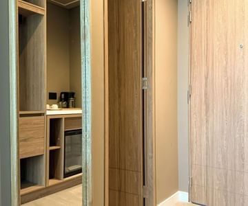 Guest room entrance with wooden doors and a minibar beneath a countertop at Unika Hotels, the best places to stay in Bogota