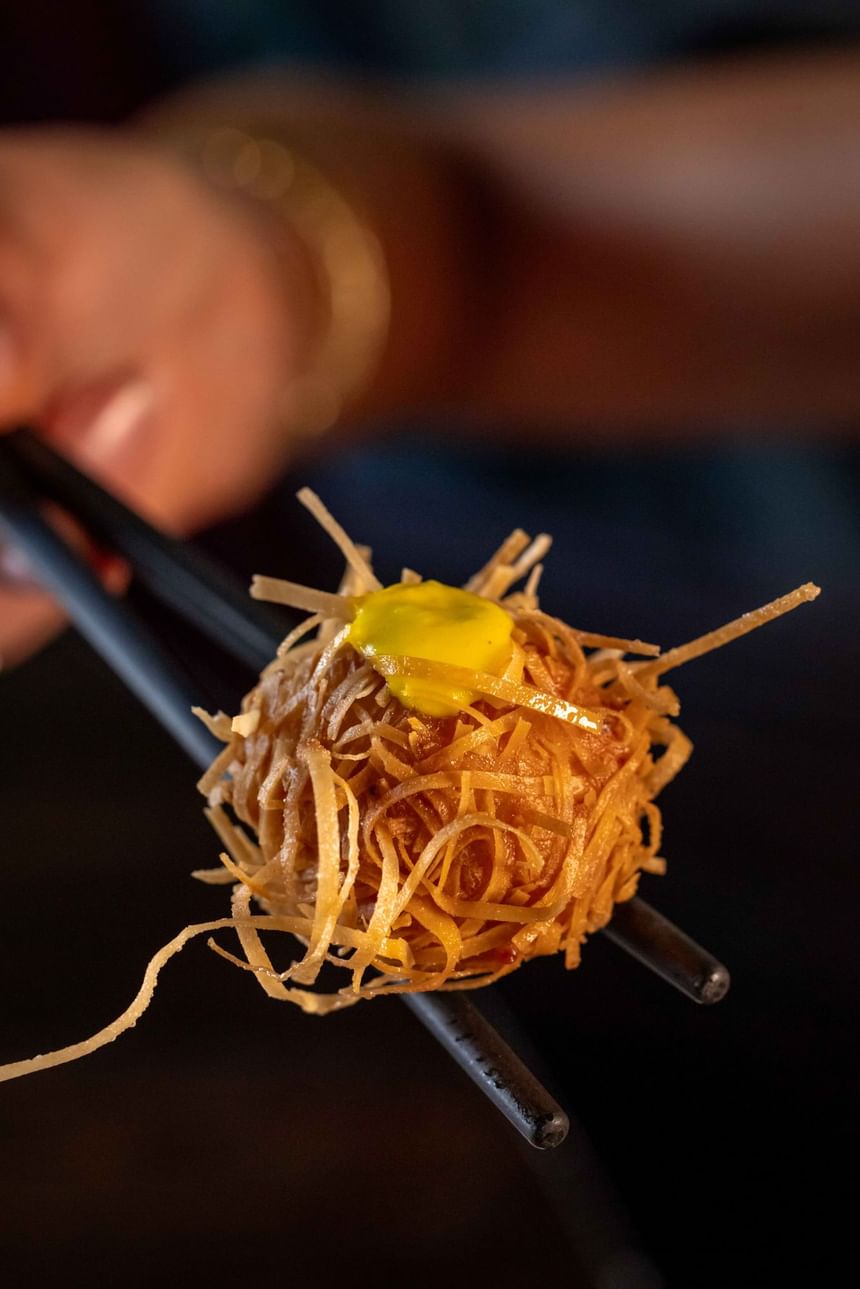 A person holding a Mala and Shrimp Dumpling, a high tea offering available at Grand Orient Oriental High Tea.