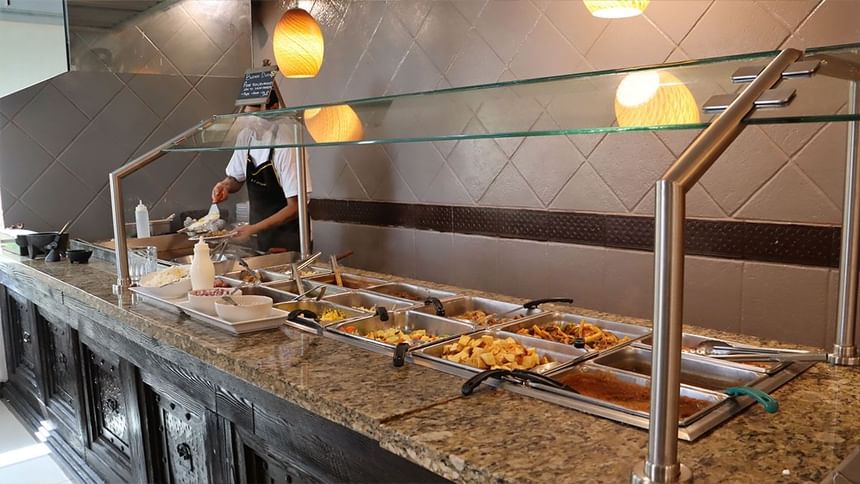 Bufé con bandejas calientes y chef preparando platos bajo lámparas colgantes en Fonda De Hermosillo, Araiza Hermosillo 