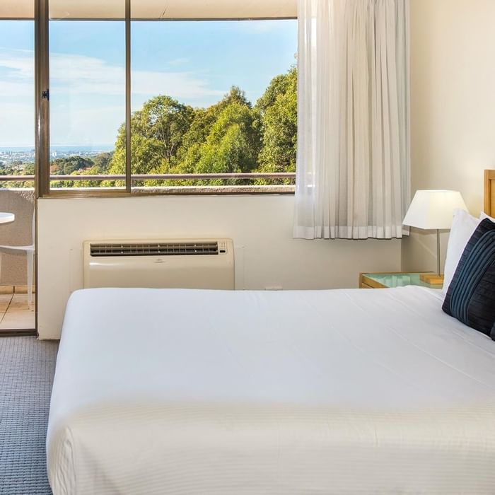 King bed in Privilege King room with a balcony lounge overlooking the distant city at Mercure Charlestown