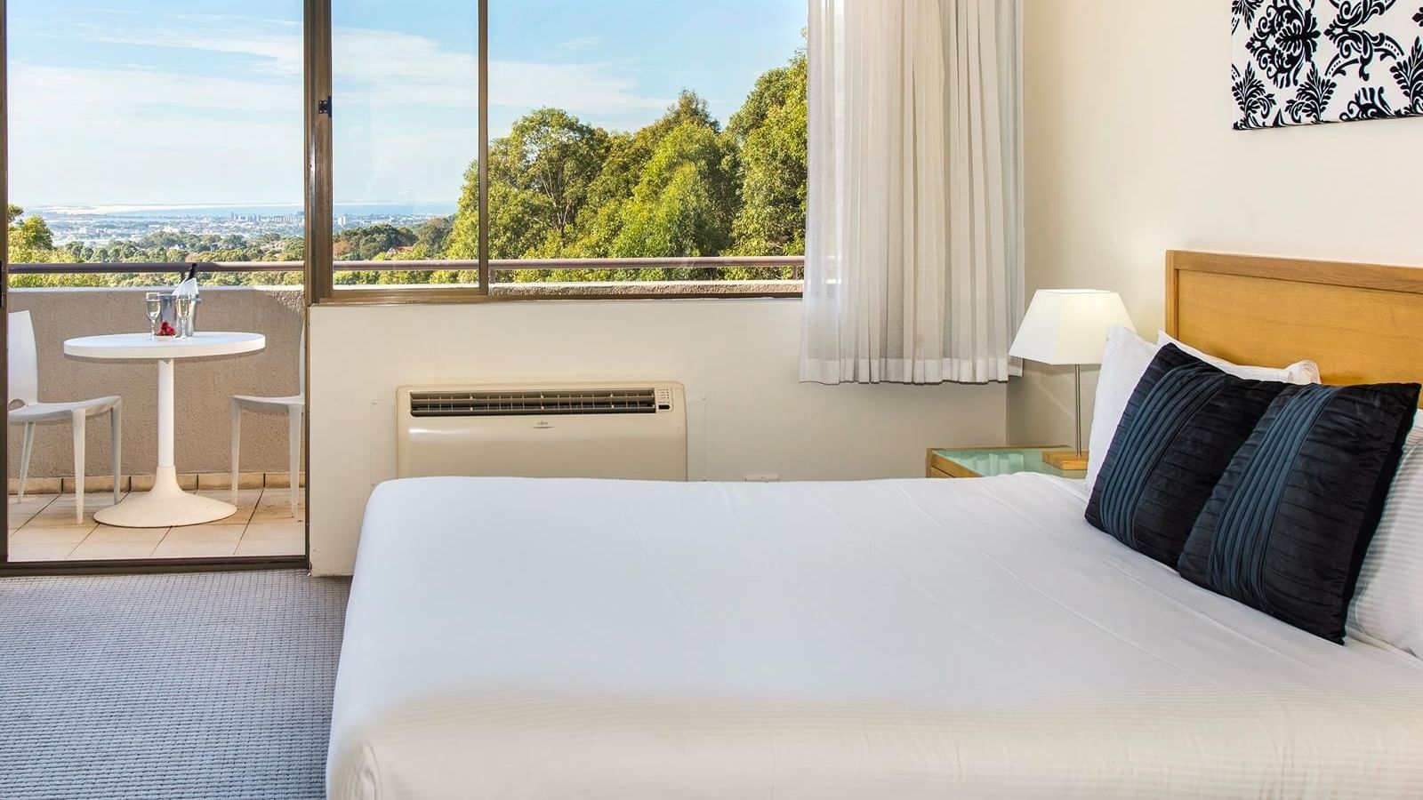 King bed in Privilege King room with a balcony lounge overlooking the distant city at Mercure Charlestown