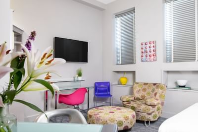 Work desk, TV, comfy chairs & fresh flowers near the kitchenette in Queen Premiere Blast at Retro Suites Hotel