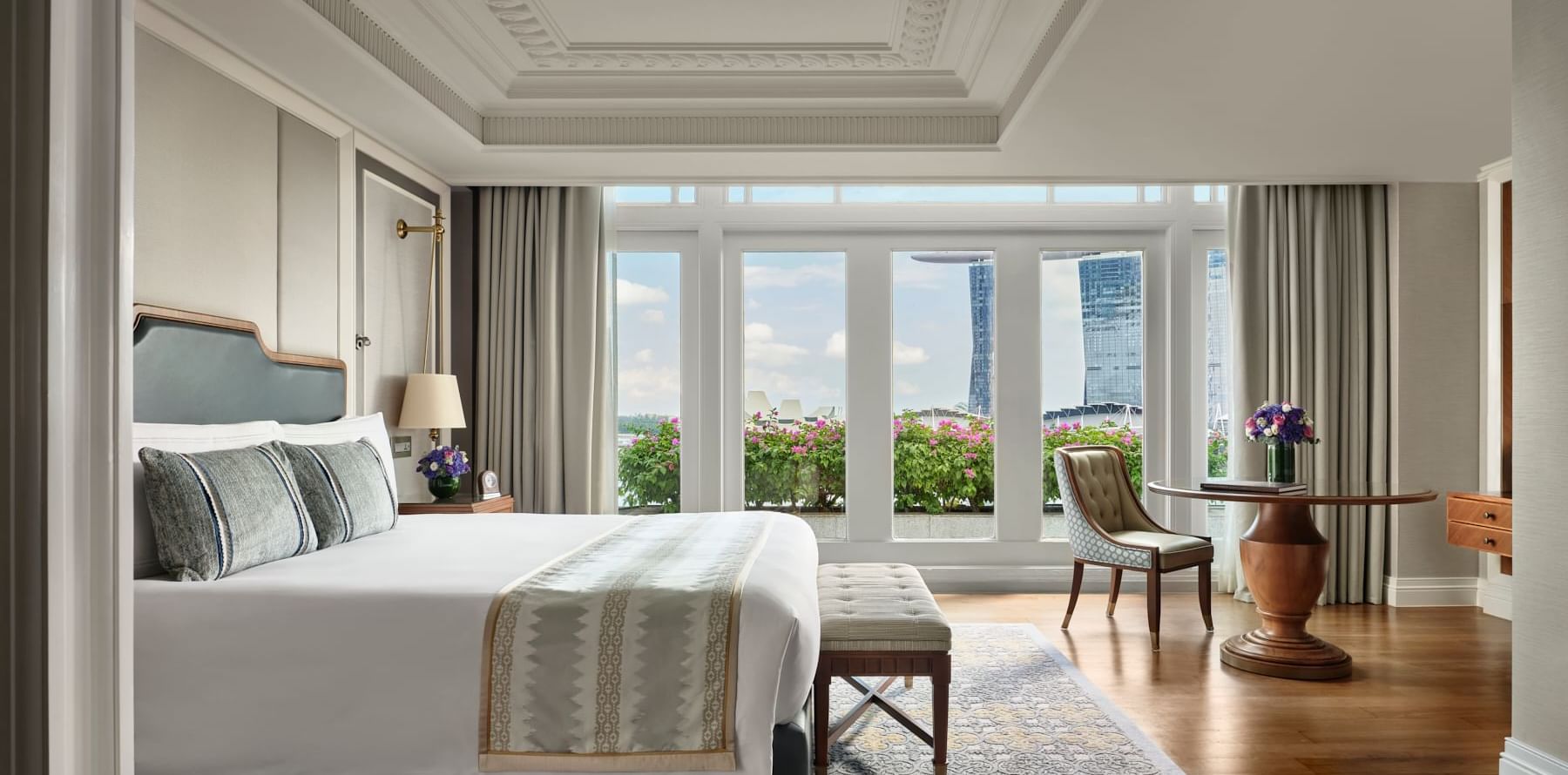 Workspace by the bed in Fullerton Suite with wooden floors at The Fullerton Hotel Singapore