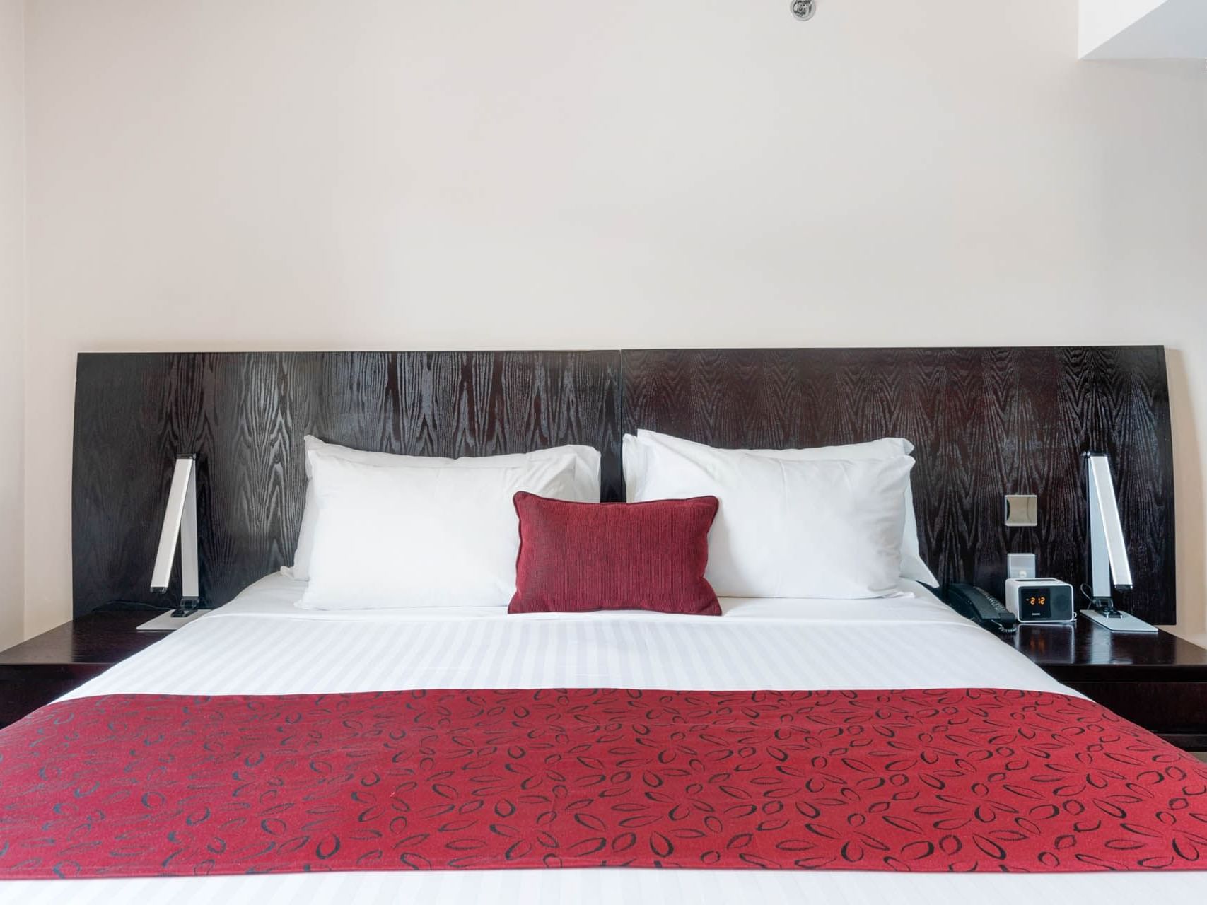 King bed with a wooden headboard in One Bedroom Suite at Grand Chancellor Launceston