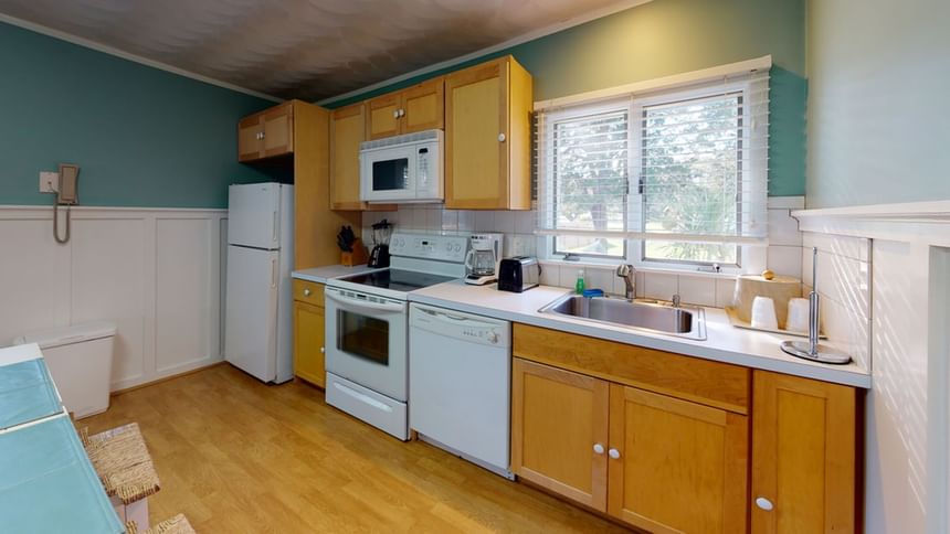 Kitchen with wooden cabinets and stainless-steel appliances in Nick Cottage at Breezeway Boutique Hotel