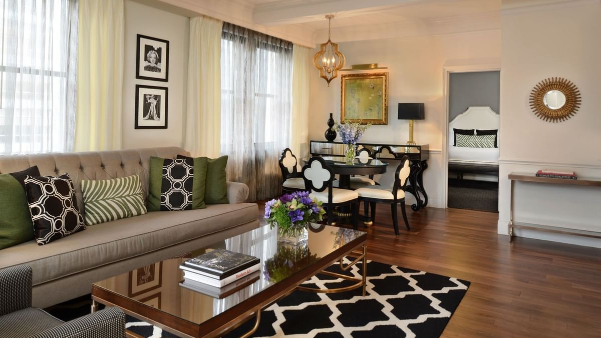 Patterned rug with grey sofa, and dining area with black & white chairs in Marion Suite at Warwick New York