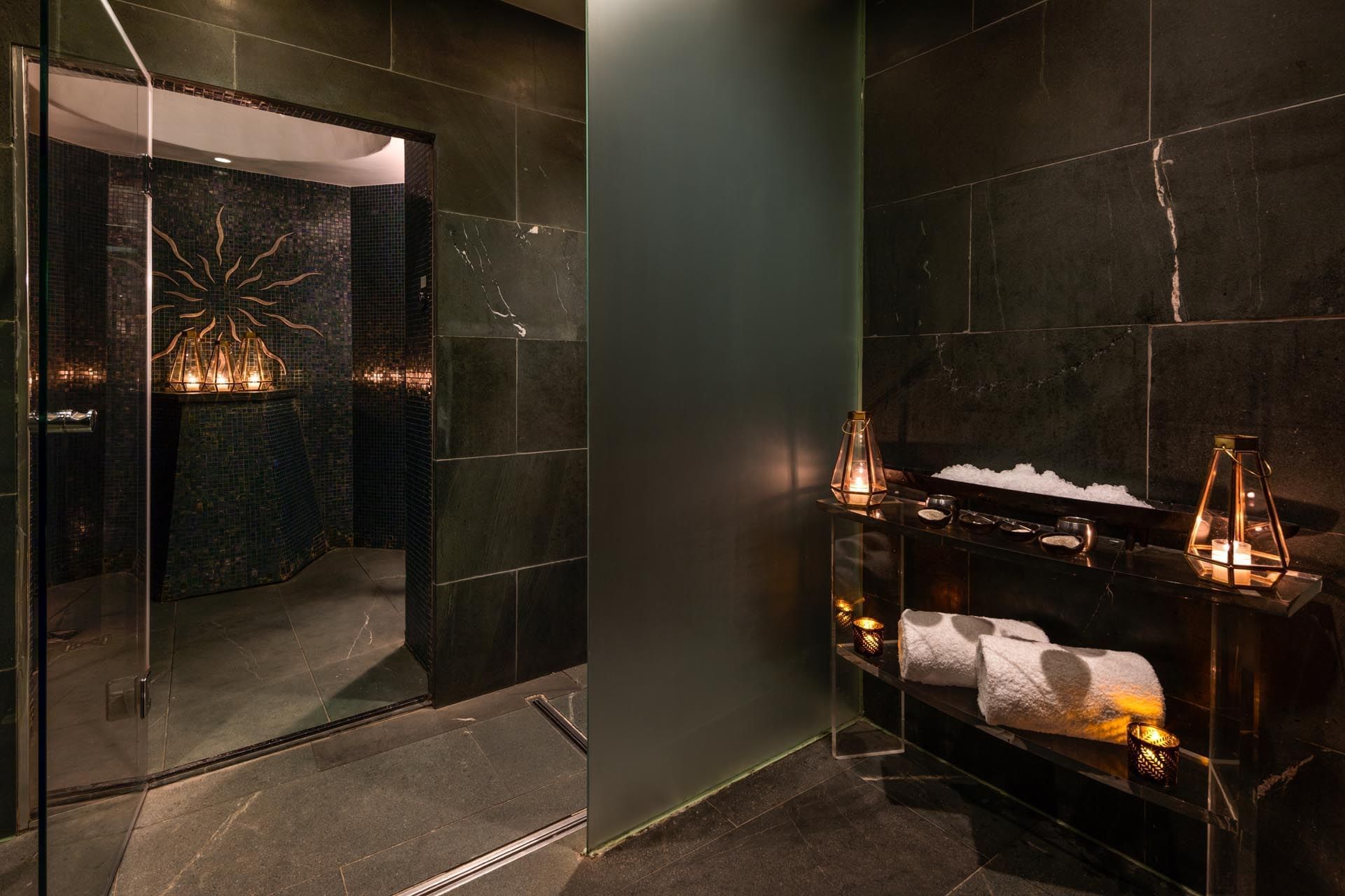 Interior of The May Fair Spa steam room with mood lighting and folded towels at The May Fair Hotel