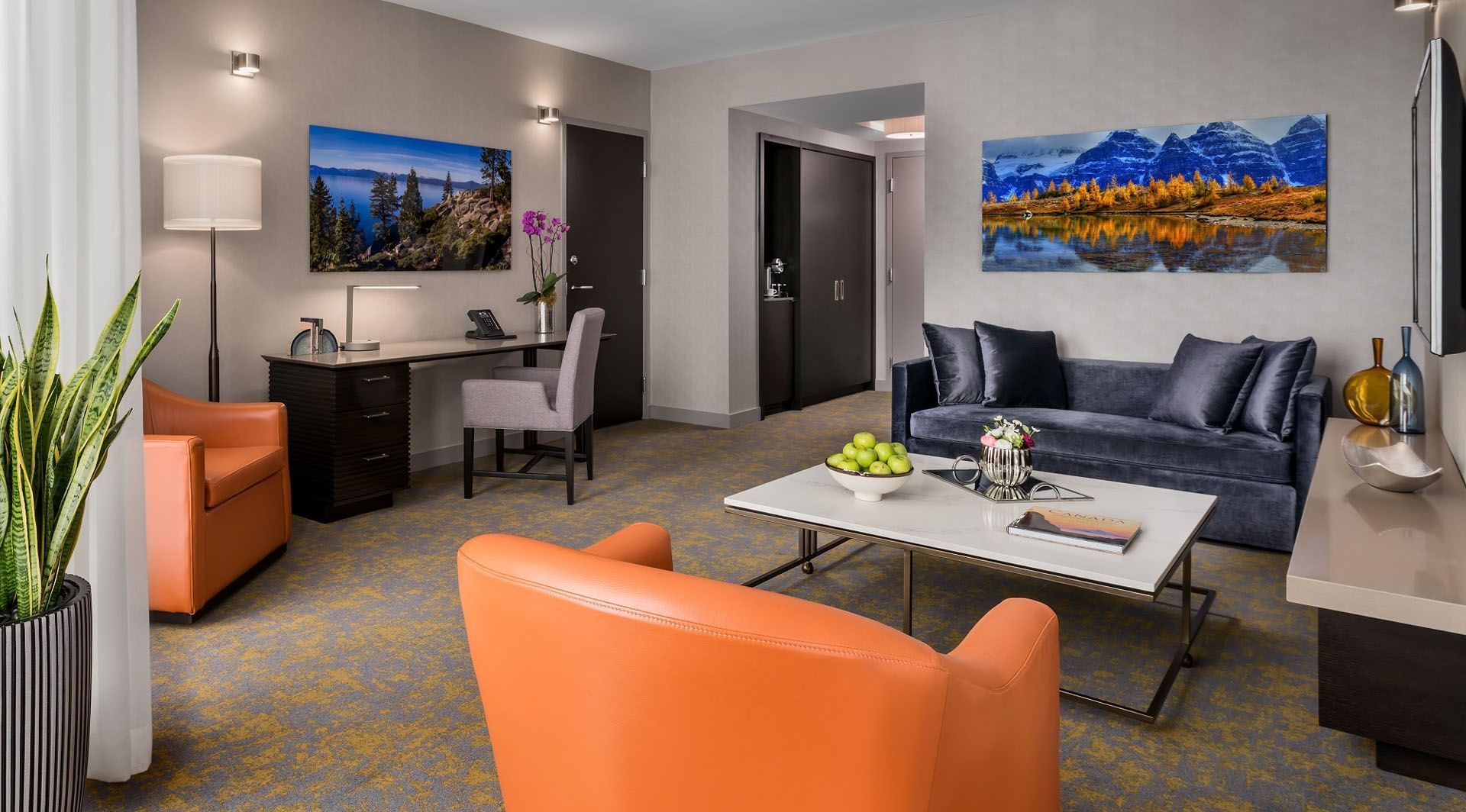 One Bedroom Suite seating area with armchairs beside coffee table and dark blue sofa with desk at Hotel X Toronto