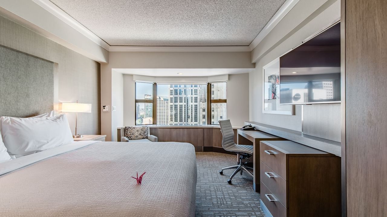 Hotel guestroom with king bed, TV, and desk