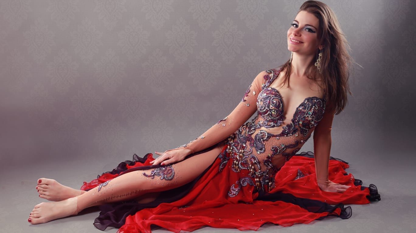 Bauchtänzerin liegt in rotem Kostüm auf dem Boden