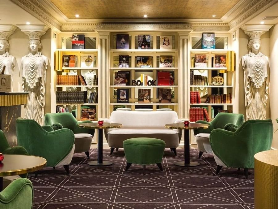 Chic library lounge with green velvet chairs and bookcases at Hotel Barsey by Warwick