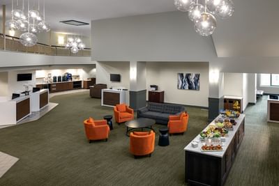 Lobby featuring armchairs with a buffet counter under spherical chandeliers at Spencer Hotel, best hotels in London Ontario