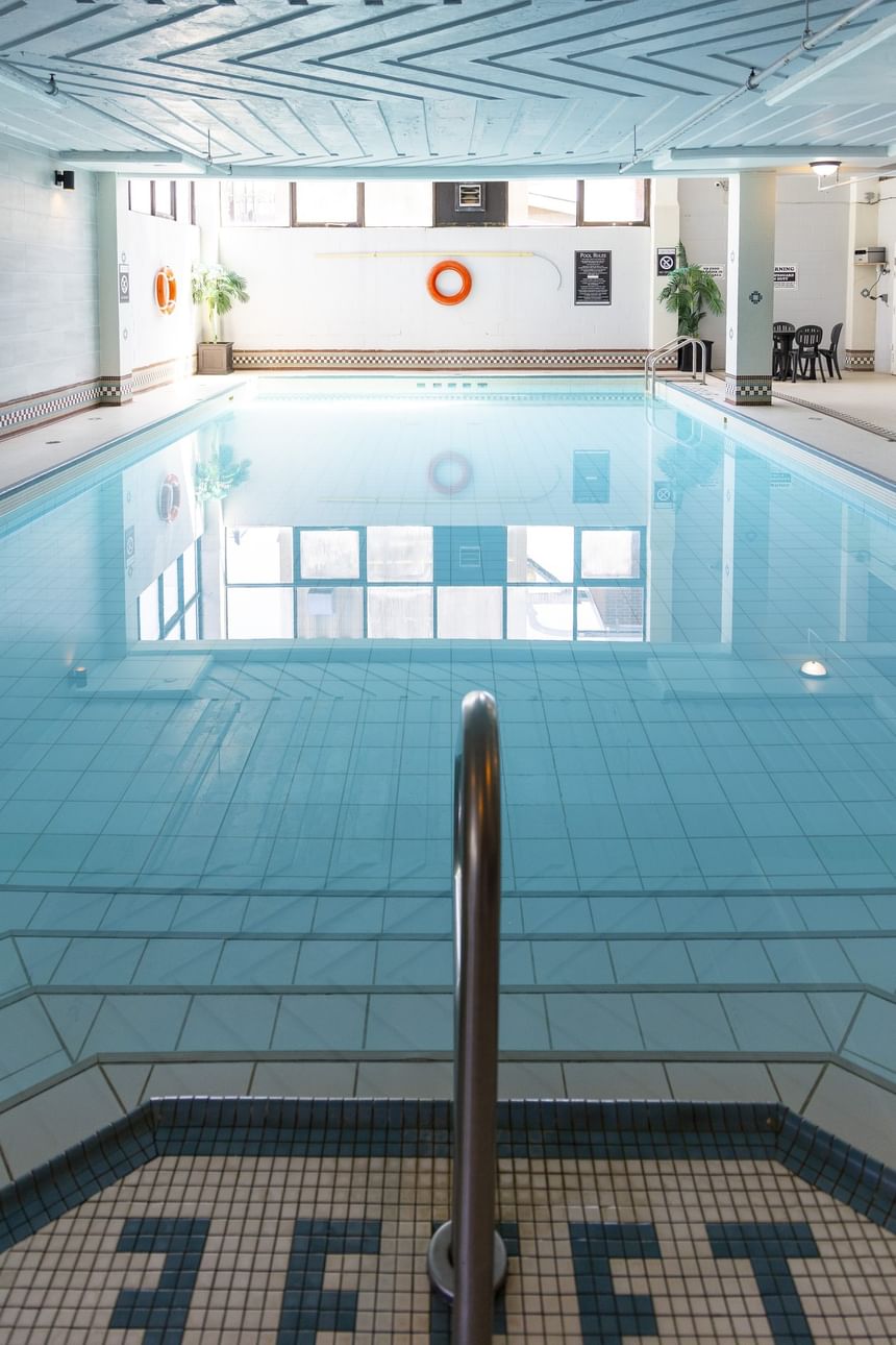 Large indoor swimming pool with blue tiles, clear water, and safety rings on the wall at Rodd Grand Yarmouth