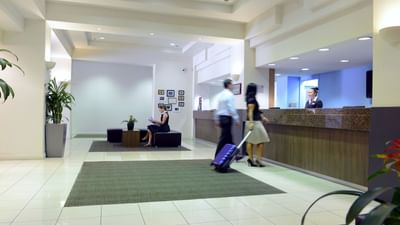Man with a woman carrying a luggage at the reception of Grosvenor Hotel Adelaide