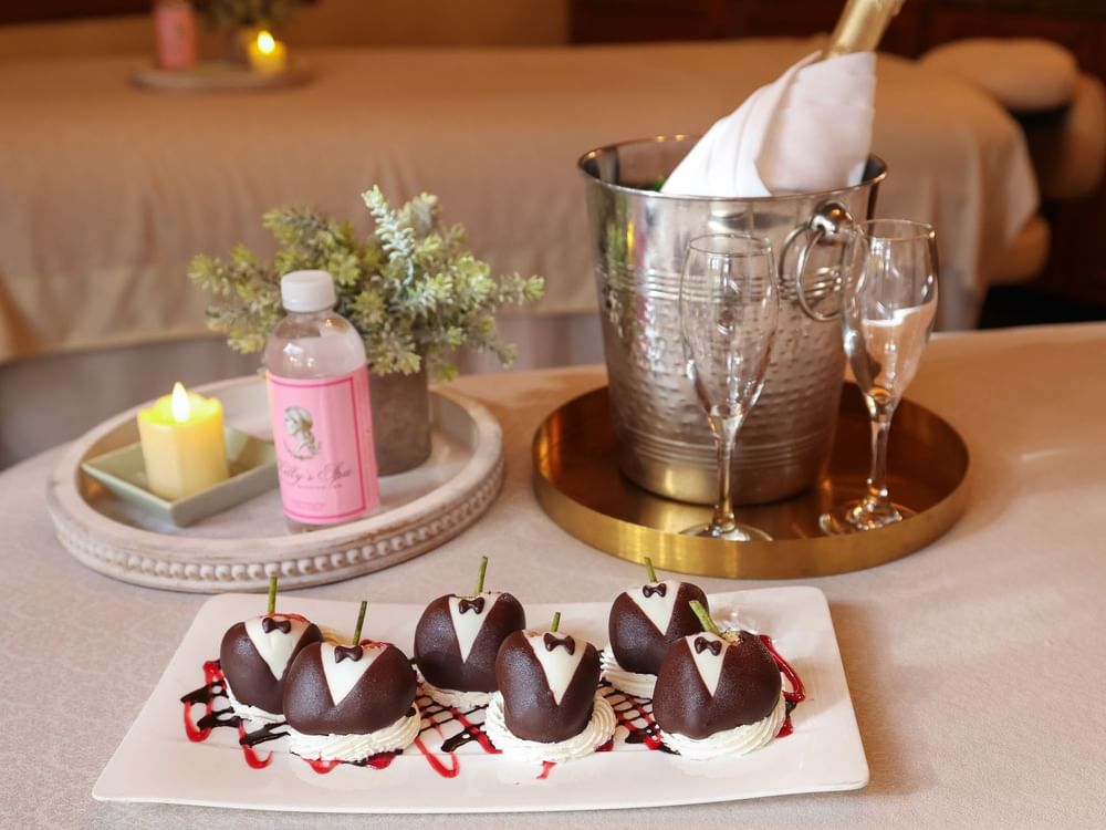 Tuxedo-decorated chocolate strawberries on a plate next to champagne for a romantic spa celebration at Kelly's Spa