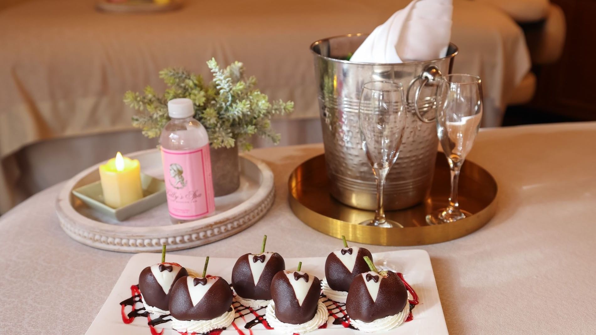 Tuxedo-decorated chocolate strawberries on a plate next to champagne for a romantic spa celebration at Kelly's Spa