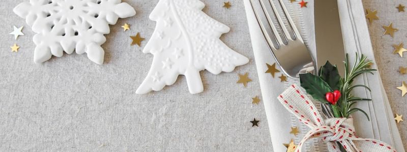 Festive In-Villa Indulgence with snowflakes, Christmas tree, stars, and decorated cutlery on a napkin.