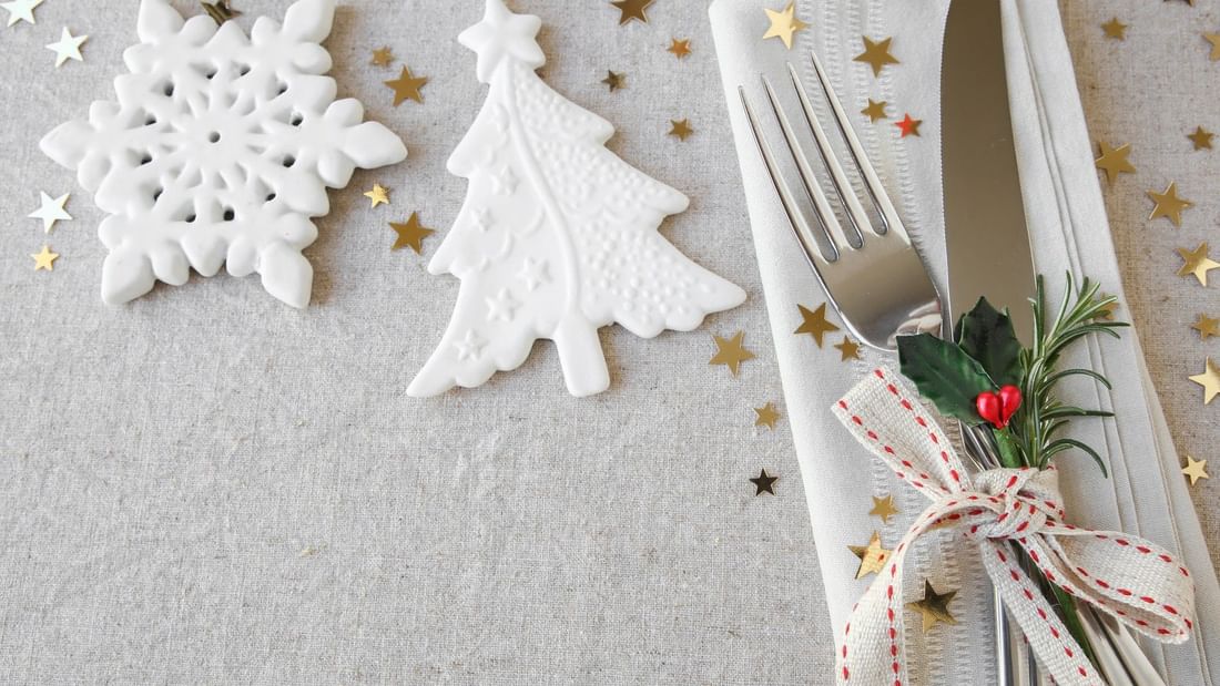 Festive In-Villa Indulgence with snowflakes, Christmas tree, stars, and decorated cutlery on a napkin.
