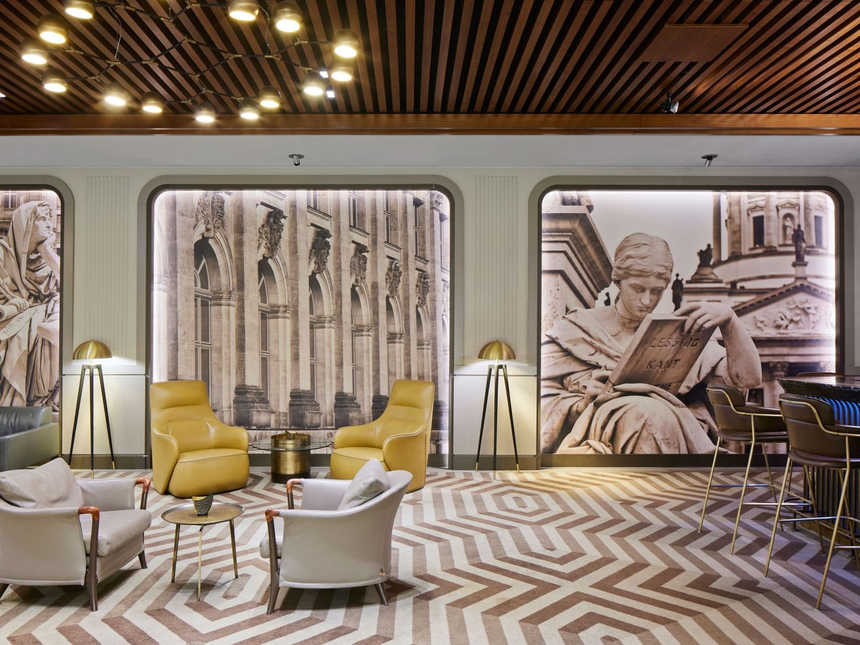 Elegante Lounge mit gelben Sesseln, stilvollen Lampen, antiken Wandmalereien und Theke – Titanic Chaussee Berlin.