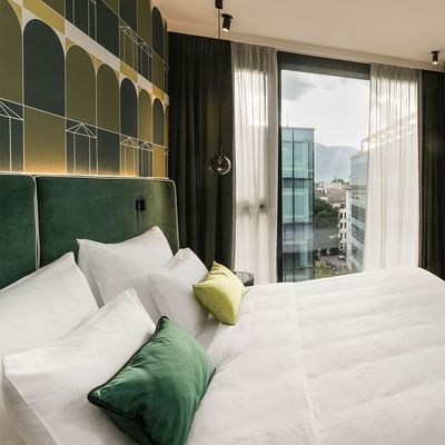 Camera Grand Deluxe Corner con vista sulla città e TV al Falkensteiner Hotel Bozen WaltherPark a Bolzano.