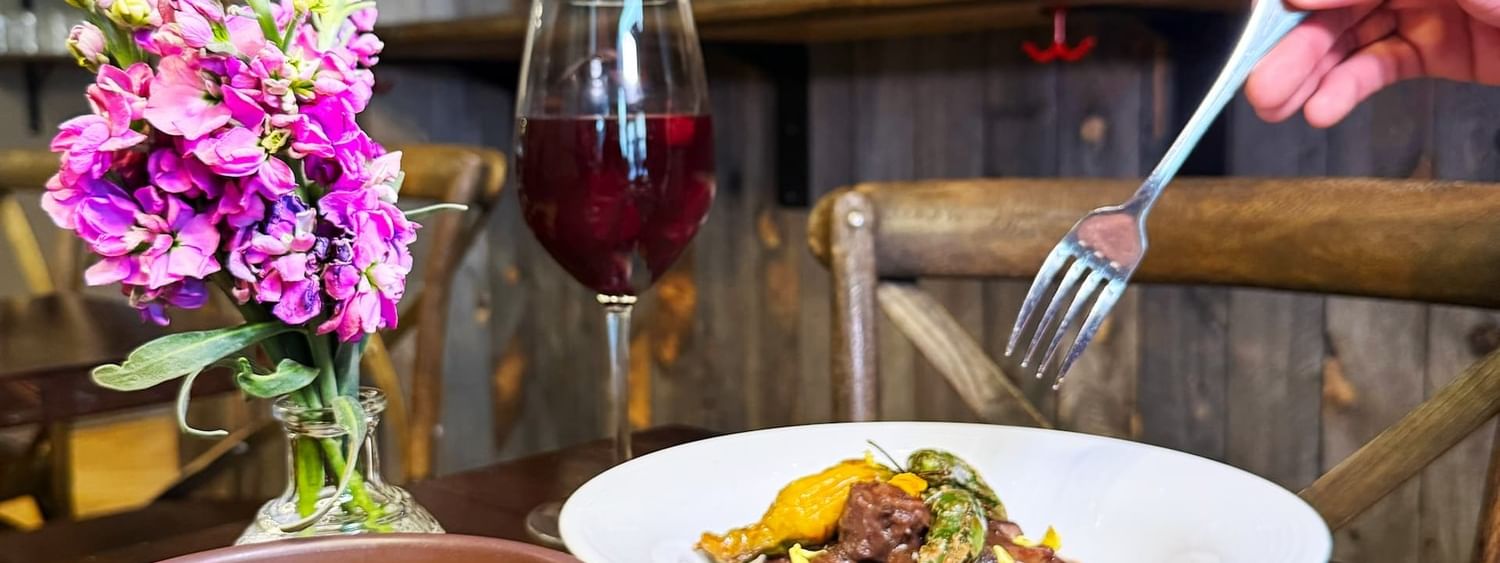 Beef stew by a bowl of soup and spicy potatoes near a wine glass in BOTA at Warwick San Francisco